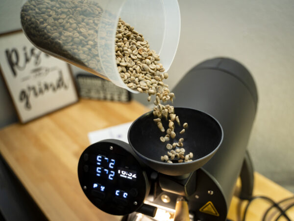 Green Colombian coffee beans pouring into the roaster